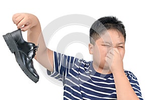 Disgusted boy holding a pair of smelly leather shoes