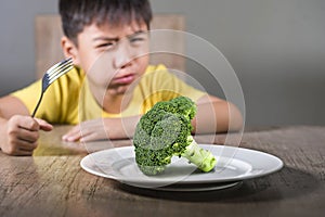 Disgusted child refusing to eat healthy green broccoli feeling upset in kid nutrition education on healthy fresh food and young