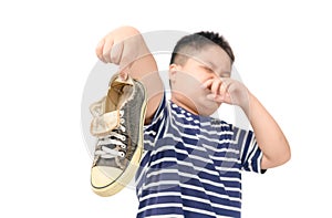 Disgusted fat boy holding a pair of smelly shoes