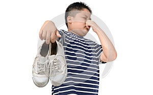 Disgusted fat boy holding a pair of smelly shoes