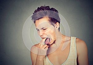 Disgusted man with finger in mouth displeased ready to throw up