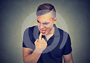 Disgusted man with finger in mouth ready to throw up