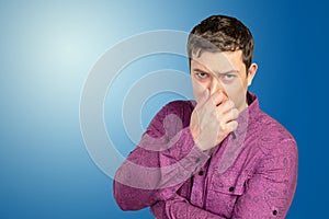 Disgusted man pinches nose with fingers