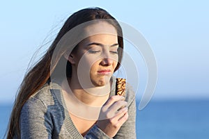 Disgusted woman tasting a bad energy bar