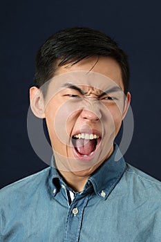 Disgusted young Asian man crying and making face