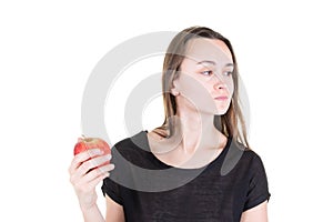 Disgusted young woman holding red apple and looking aside in start vegetarian healthy diet