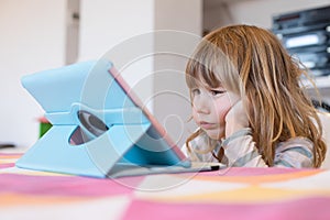 Disgusting expression of little child watching digital tablet