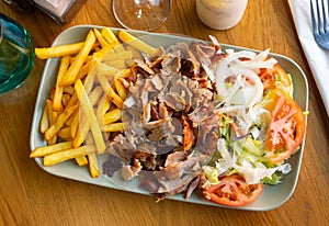 Dish with appetizing assorty of Armenian cuisine of delicious shish kebab, french fries, baked vegetables, tomatoes