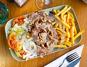 Dish with appetizing assorty of Armenian cuisine of delicious shish kebab, french fries, baked vegetables, tomatoes