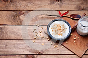 Dish of cereal with milk, glass of milk and wooden spoon