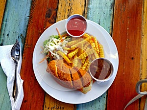 dish of chicken cordon bleu with french fries and some sauce also salad