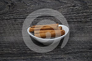 Dish of cinnamon sticks on a rustic wood background