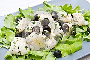 Dish of cod salad with black olives