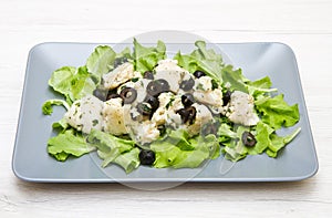 A dish of cod salad with black olives