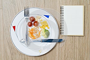 Dish with cutlery, healthy food and a notebook on a wooden background