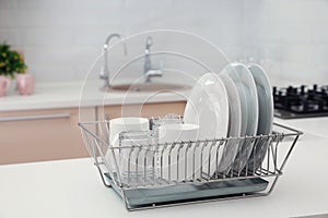 Dish drainer with clean dinnerware on table