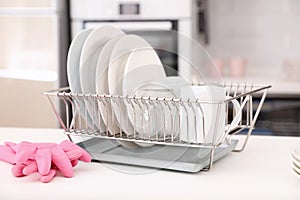 Dish drainer with clean dinnerware on table