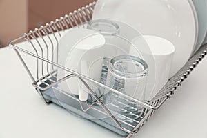 Dish drainer with clean dinnerware on table