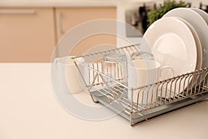 Dish drainer with clean dinnerware on table