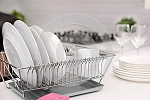 Dish drainer with clean dinnerware on table