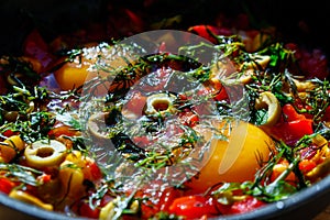 Dish egg in a frying pan with olives, pepper and greens