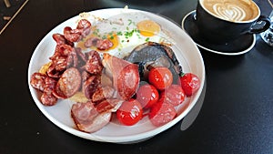 A dish of English full breakfast with a lot of sausage, eggs, tomatoes, and large piece of mushroom