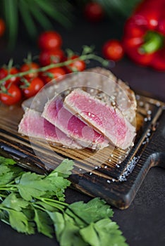 dish fish tuna steak fried in pieces on the grill with vegetables on a plank