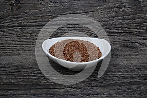 Dish of flax seed on a rustic wood background