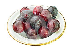 Dish of fresh plums on white background