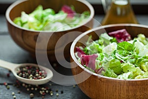 A dish of fresh salad frisse, Romano and radiccio with olive oil, salt and freshly ground percec in a wooden bowl
