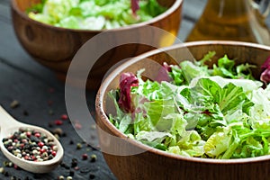A dish of fresh salad frisse, Romano and radiccio with olive oil, salt and freshly ground percec in a wooden bowl
