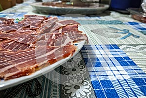Dish of freshly sliced Iberian ham on blue tablecloth