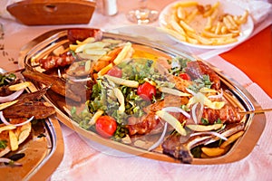 A dish of fried meat, vegetables, French fries, tomatoes