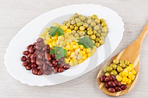 Dish with green peas, beans, sweet corn, parsley and spoon