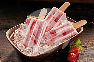Dish of healthy fresh strawberry popsicles on ice