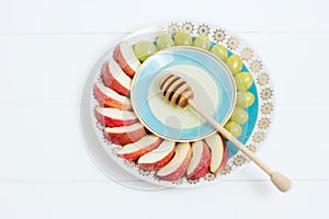 Dish with honey, fruit on white background. Jewish NY, Rosh Hashanah. Selective focus, small depth of field, lensbaby