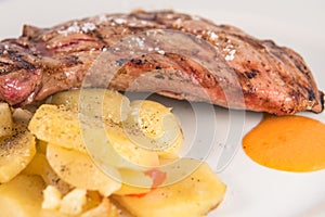 Dish of Iberian pork presa with baked potato slices.