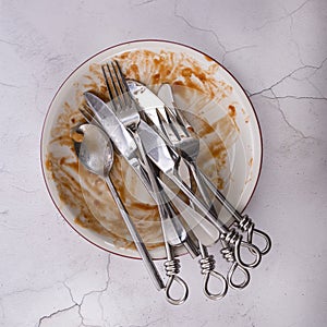 Dish of leftovers with knifes, forks and spoon