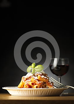 Dish with macaroni and tomato sauce on the wooden table