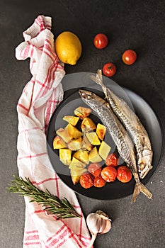 Dish of mackerel with potatos on black background