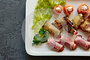 A dish with mini-canapes of salmon, eggplant and ham rolls with different fillings for a buffet and a festive table