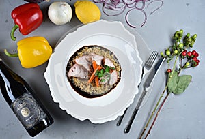 A dish of pork belly with lentils and caramen in a white plate