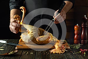 A dish of raw chicken by the hands of a cook in the kitchen of a restaurant or pub. Getting ready to cook raw rooster on a cutting