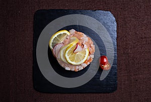dish in the restaurant of red fish with lemon on a black plate top view
