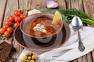 Dish of russian hodgepodge soup and other food on a wooden table