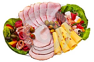 Dish with sliced smoked ham, salami rolls.