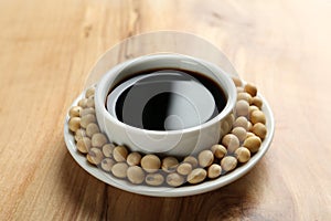 Dish of soy sauce with beans on background