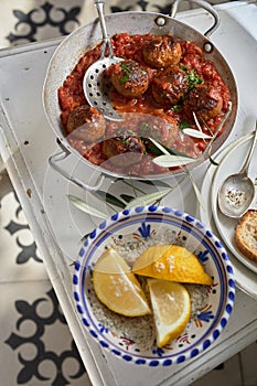 Dish of spicy meatballs with fresh lemon wedges photo