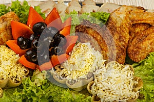 Dish from tartlets and chicken wings with the presence of lettuce leaves.