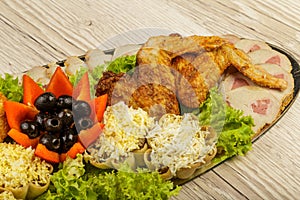 Dish from tartlets and chicken wings with the presence of lettuce leaves.